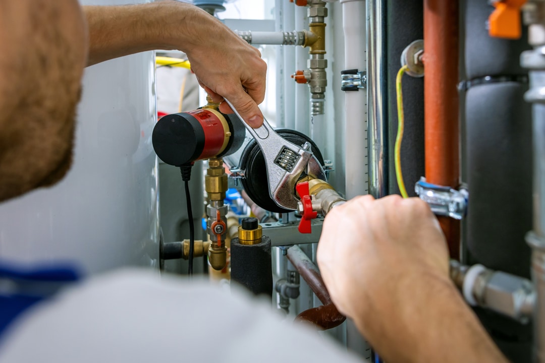Plumber tightening a pipe fitting with an adjustable wrench.