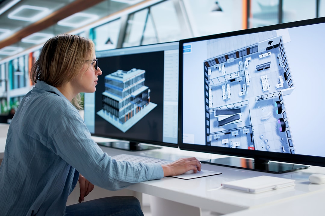 Woman designing a 3D architectural building model on screens.