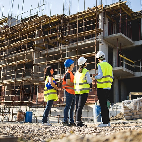 Group of four construction workers looking up at a scaffolded building.