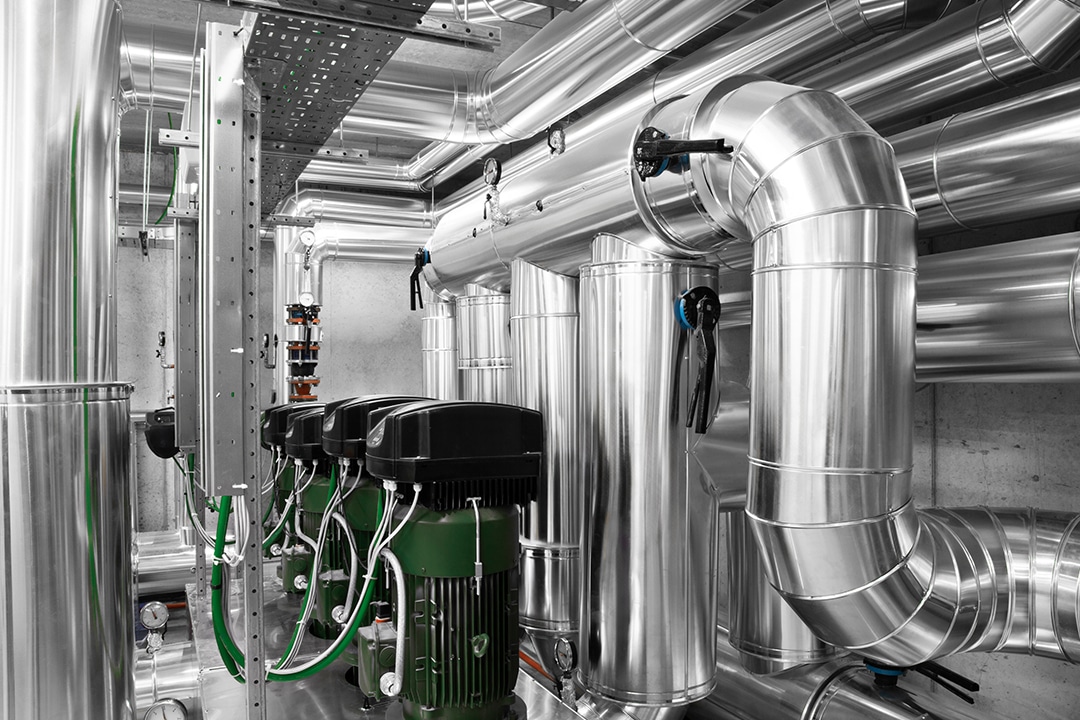 Insulated silver HVAC piping system connected to green pumps.
