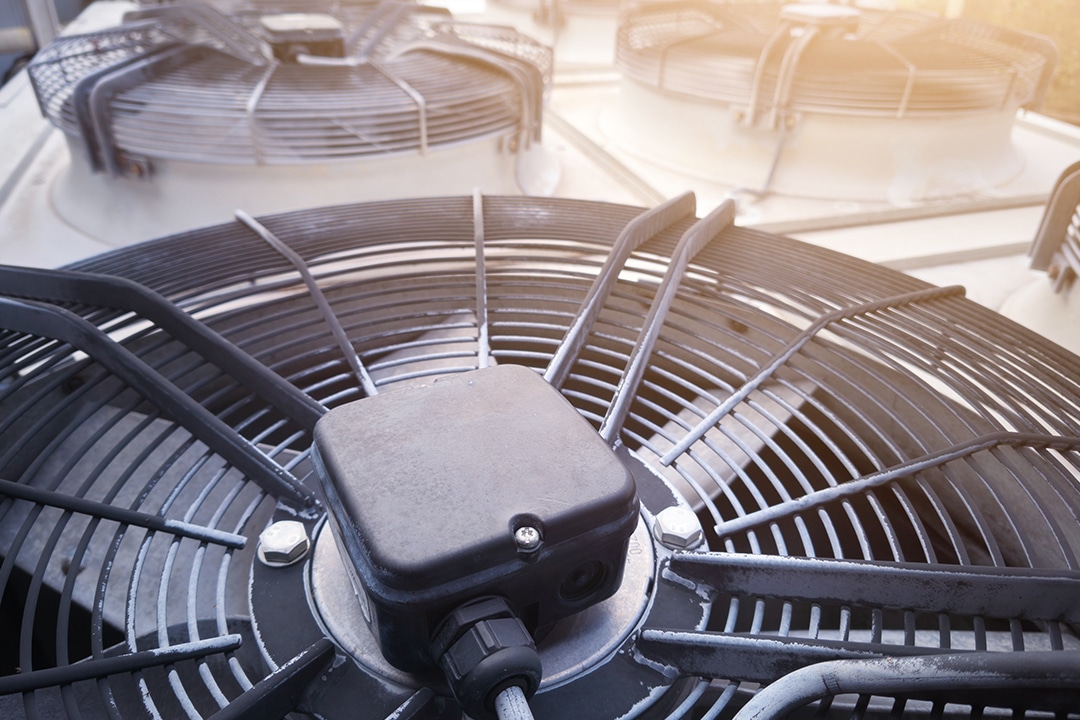 Close-up of industrial rooftop air conditioning condenser fan units.