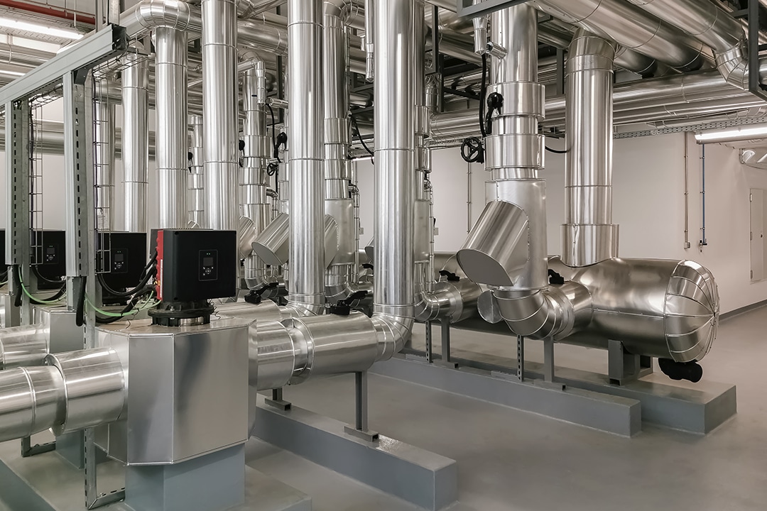Clean industrial facility with shiny, insulated silver refrigeration pipes.