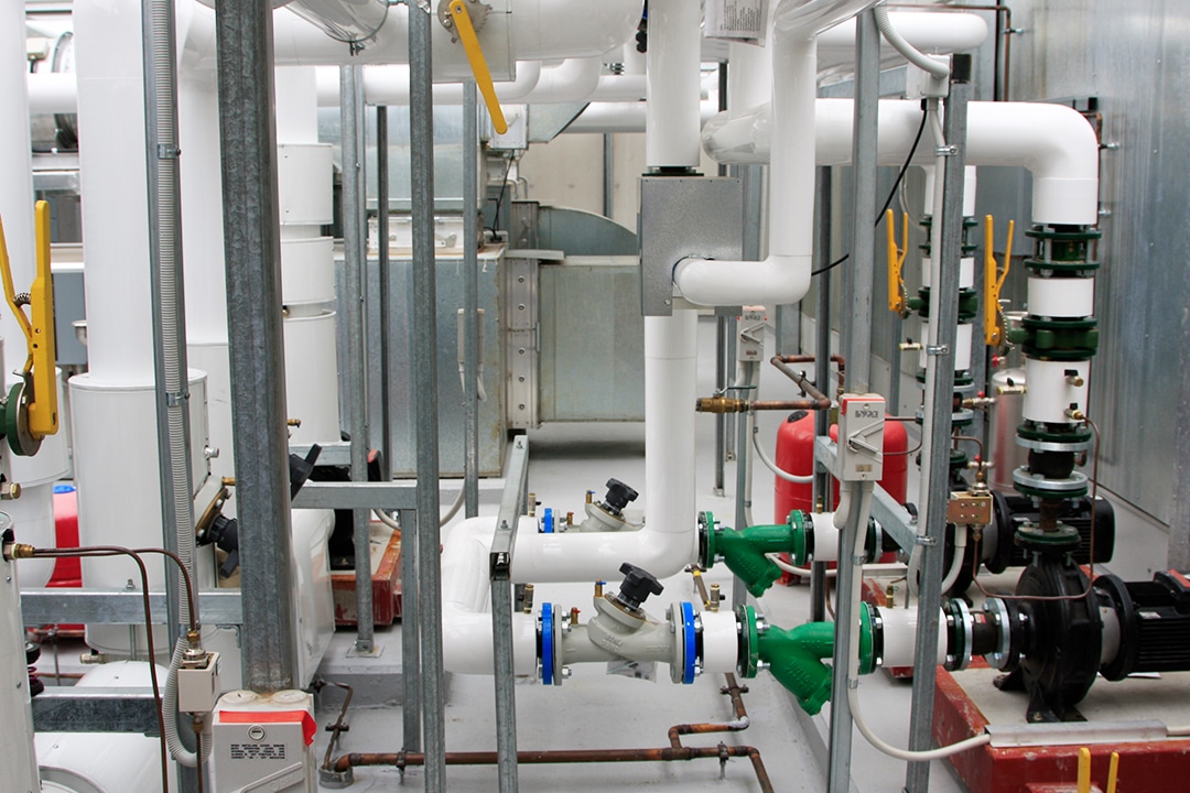Industrial utility room with white pipes and green valves.
