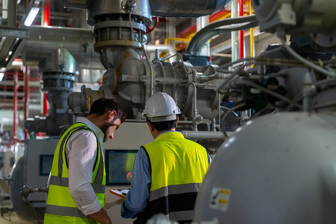 Two engineers inspecting machinery in an industrial plant.