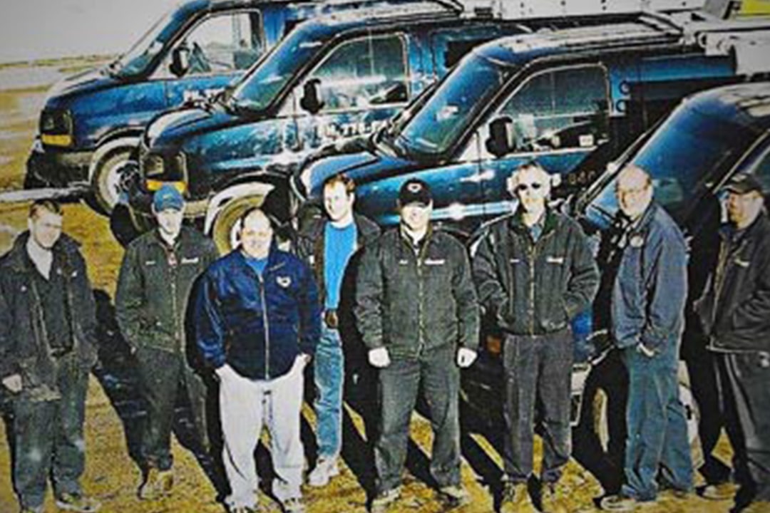 Group of service technicians standing by company work vans.