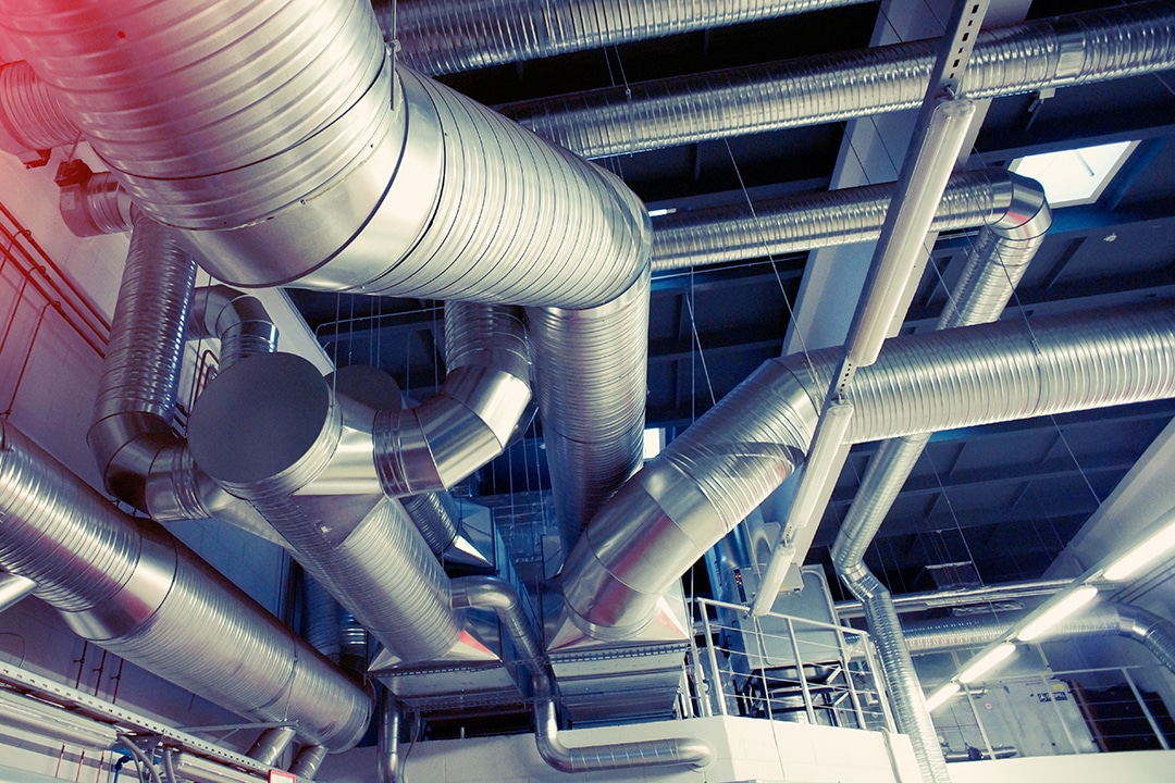 Complex system of metallic HVAC ventilation ductwork on a ceiling.